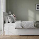 Modern white wooden platform bed with integrated pull-out storage drawer, minimalist panel headboard, and contemporary bedroom design.