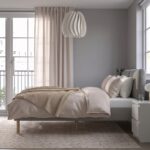 Modern beige upholstered platform bed with a cushioned fabric headboard, wooden legs, and minimalist Scandinavian bedroom design.