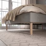 Modern beige upholstered platform bed with a cushioned fabric headboard, wooden legs, and minimalist Scandinavian bedroom design.
