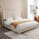 Luxury white upholstered platform bed with a tall wingback channel-tufted headboard, gold metal accents, and a contemporary minimalist design.