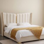 Luxury white upholstered platform bed with a tall wingback channel-tufted headboard, gold metal accents, and a contemporary minimalist design.