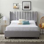 Modern grey upholstered platform bed with a tall wingback vertical channel-tufted headboard and solid wood legs in a contemporary bedroom.