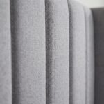 Modern grey upholstered platform bed with a tall wingback vertical channel-tufted headboard and solid wood legs in a contemporary bedroom.