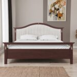 Classic walnut solid wood upholstered platform bed with an elegant arched fabric headboard and decorative brass accents in a sophisticated bedroom.