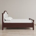 Classic walnut solid wood upholstered platform bed with an elegant arched fabric headboard and decorative brass accents in a sophisticated bedroom.