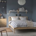 Modern natural wood platform bed with open slatted headboard in a contemporary Scandinavian bedroom featuring minimalist styling and durable wooden frame.