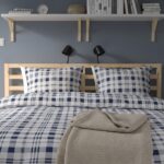 Modern natural wood platform bed with open slatted headboard in a contemporary Scandinavian bedroom featuring minimalist styling and durable wooden frame.