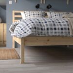 Modern natural wood platform bed with open slatted headboard in a contemporary Scandinavian bedroom featuring minimalist styling and durable wooden frame.