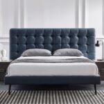Modern blue upholstered platform bed with button-tufted headboard, wooden legs, and low-profile contemporary frame for stylish bedroom décor.