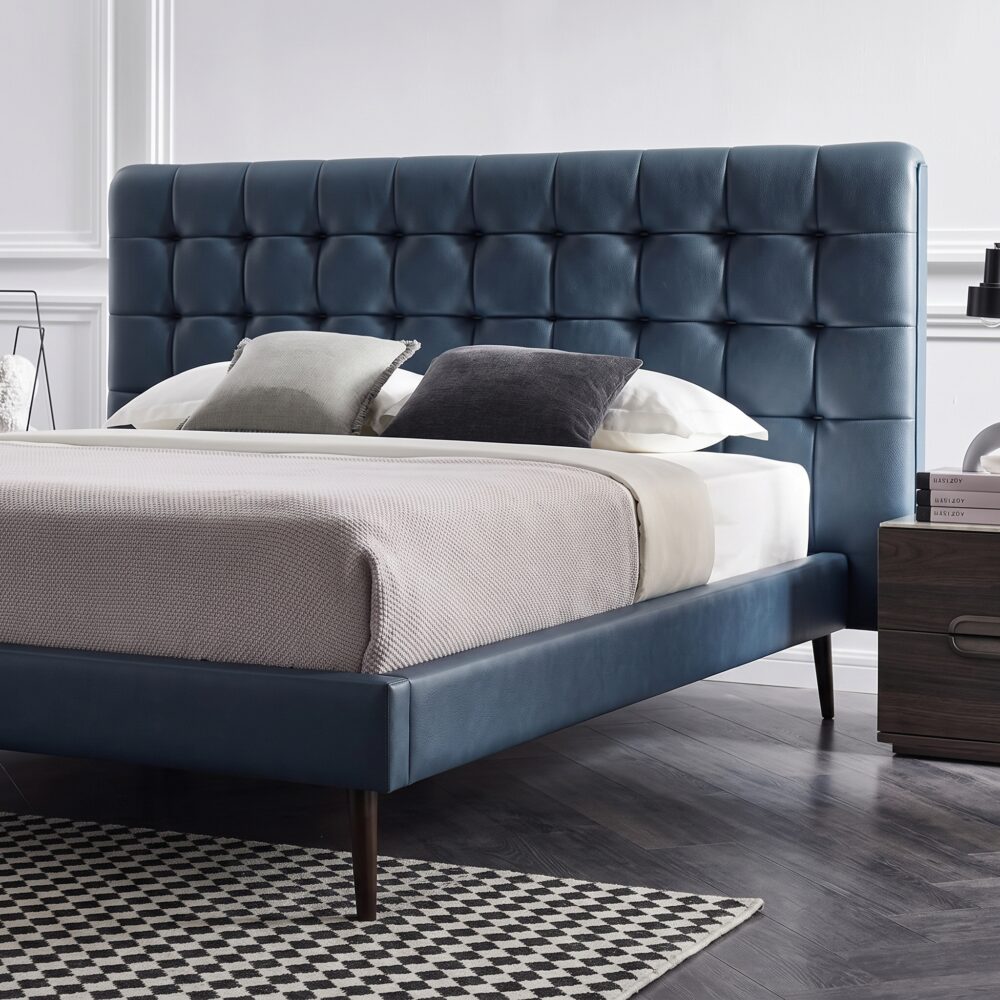 Modern blue upholstered platform bed with button-tufted headboard, wooden legs, and low-profile contemporary frame for stylish bedroom décor.