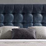 Modern blue upholstered platform bed with button-tufted headboard, wooden legs, and low-profile contemporary frame for stylish bedroom décor.