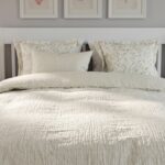 Modern white platform bed with clean panel headboard and pull-out storage drawer in a contemporary bedroom setting.