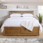 Modern natural wood platform bed with slatted headboard and storage-style base in contemporary bedroom.
