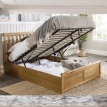 Modern natural wood platform bed with slatted headboard and storage-style base in contemporary bedroom.