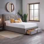 Modern gray upholstered platform bed with padded headboard and four pull-out storage drawers in a contemporary bedroom.