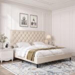 Modern beige upholstered platform bed with button tufted nailhead headboard, low-profile frame, sturdy wooden slats, and elegant contemporary bedroom design.