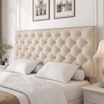 Modern beige upholstered platform bed with button tufted nailhead headboard, low-profile frame, sturdy wooden slats, and elegant contemporary bedroom design.