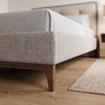 Modern beige upholstered platform bed frame with button-tufted headboard, walnut wood legs, and contemporary minimalist bedroom décor.