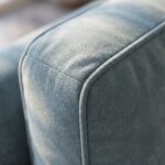 Modern light gray 3-seater fabric sofa with premium upholstery, plush cushions, rounded armrests, and a sturdy wooden base in a contemporary living room.