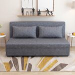 Modern grey fabric sofa cum bed with removable cushions, integrated side storage pockets, and convertible sleeper design in a contemporary living room.