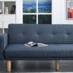 Modern navy blue fabric sofa cum bed with button-tufted backrest, wooden legs, and fold-flat convertible design in a contemporary living room.
