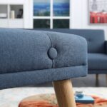 Modern navy blue fabric sofa cum bed with button-tufted backrest, wooden legs, and fold-flat convertible design in a contemporary living room.