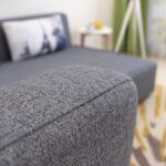 Modern grey fabric sofa cum bed converted into a spacious sleeper bed with dual side storage pockets, premium upholstery, high-density foam cushions, and contemporary design for living room or guest room.
