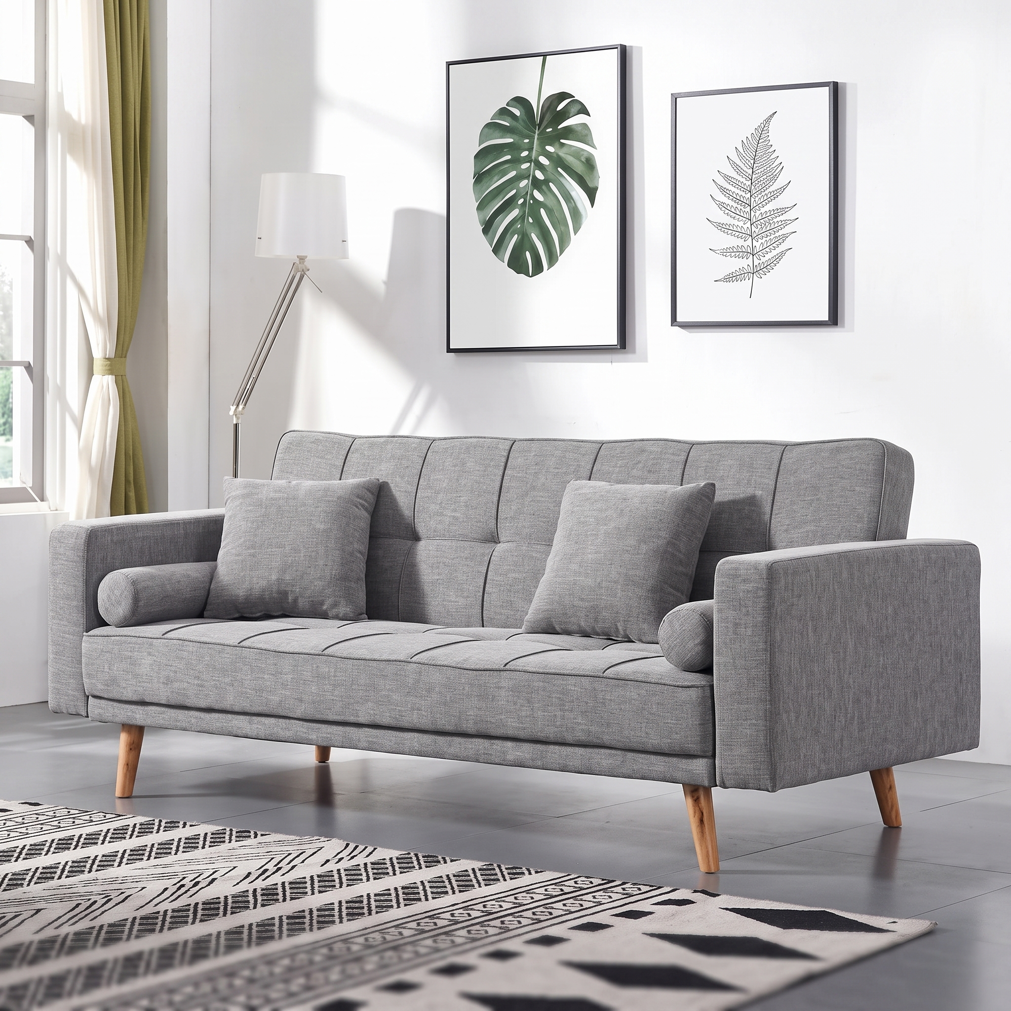 Modern grey fabric convertible sofa bed with tufted backrest, wooden legs, square cushions, bolster pillows, and Scandinavian design for living room furniture.