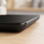 Homslux black tempered glass digital kitchen scale on a wooden countertop showing LED weight readout
