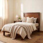 Dark walnut brown single bed with a framed rectangular panel headboard, raised wooden-style legs, cream bedding, knitted beige throw, and neutral bedroom décor.