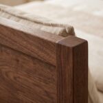 Solid walnut wood single bed frame featuring a tall wooden headboard styled with neutral linen pillows and bedding next to a matching bedside table.