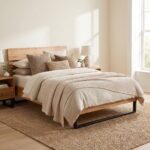 Modern wooden single bed frame with horizontal slatted headboard and black metal sled legs styled in a sunlit bedroom over a woven jute rug.