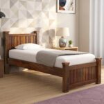 Solid wood single bed frame with mission vertical slats on headboard and footboard styled in a bright bedroom next to a nightstand.