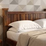 Solid wood single bed frame with mission vertical slats on headboard and footboard styled in a bright bedroom next to a nightstand.