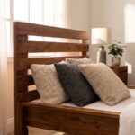 Rustic solid acacia wood single bed frame with horizontal slatted headboard styled with neutral beige waffle bedding in a sunlit bedroom.