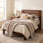 Rustic solid acacia wood single bed frame with horizontal slatted headboard styled with neutral beige waffle bedding in a sunlit bedroom.