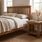 Rustic solid oak wood single bed frame featuring a vertical slatted headboard styled with beige linen bedding next to a matching oak nightstand.