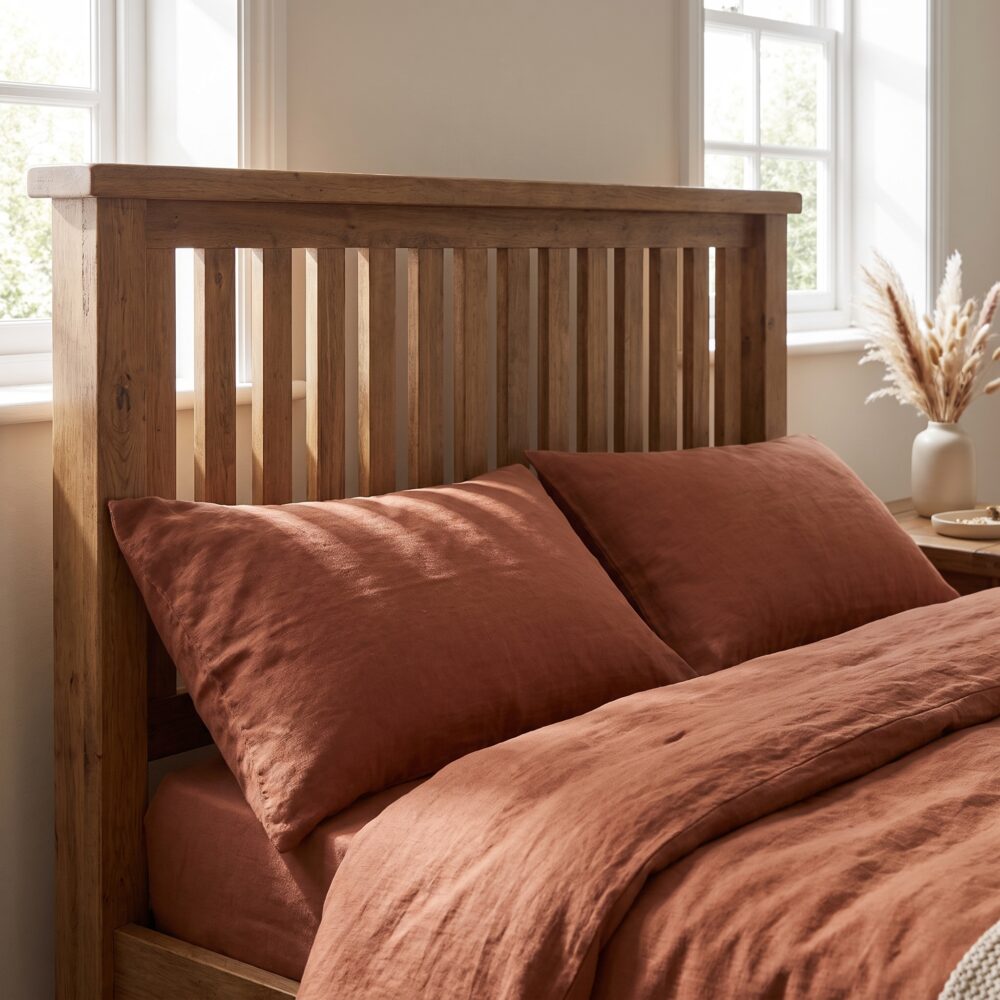 Rustic solid oak wood single bed frame featuring a vertical slatted headboard styled with beige linen bedding next to a matching oak nightstand.