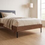 Japandi style single bed frame with charcoal horizontal upholstered headboard and warm walnut rails in a minimalist sunlit bedroom.