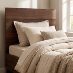 Modern walnut wood single bed frame with matching solid headboard and footboard styled with light beige bedding in a sunlit bedroom.