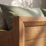 Wooden single bed frame with hydraulic gas-lift mechanism open showing folded blankets and towels stored inside under-bed compartment.