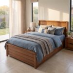 Wooden single bed frame with hydraulic gas-lift mechanism open showing folded blankets and towels stored inside under-bed compartment.